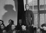August Blei, a defendant at the trial of 61 former camp personnel and prisoners from Mauthausen, stands in his place in the defendants' dock.