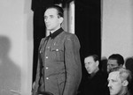 Dr. Friedrich Entress, defendant at the trial of 61 former camp personnel and prisoners from Mauthausen, stands in his place in the defendants' dock.