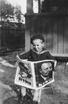 Four-year-old Wilhelm Beigel reads a movie magazine outside his home in Vilna.