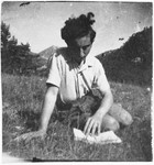 Jewish refugee Eryk Goldfarb reads a book on a grassy hillside while living in hiding in Col de Menee, France.
