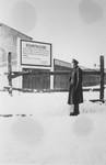 A member of Police Battalion 101 poses next to a large sign marking the entrance to the Lodz ghetto.