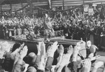 Standing in an open car, Adolf Hitler salutes a crowd lining the streets of Hamburg.