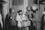 [Mock arrest of a comrade dressed up as a bearded Jewish peddlar by members of Police Battalion 101].