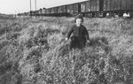 A child runs through the grass in front of a freight train.