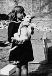 A Polish girl holding her dog in her arms views the destruction wrought by German air raids during the siege of Warsaw.