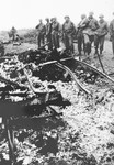 While on an inspection tour of the newly liberated Ohrdruf concentration camp, American soldiers view the charred remains of prisoners that were burned upon a section of railroad track during the evacuation of the camp.