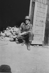 First Sergeant John H. Harris kneels in front of a pile of corpses inside a shed in the Ohrdruf concentration camp.