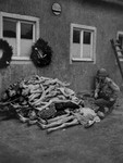 An American soldier kneeling next to a pile of corpses at Buchenwald.