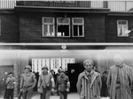 American soldiers and survivors stand by the entrance of Buchenwald.
