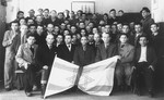 Group portrait of Jewish displaced persons holding a Zionist flag.