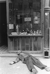 A man lies dead on the pavement in front of a shop in the Warsaw ghetto.