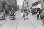 A Jewish man rides in a rickshaw on a crowded street in the Warsaw ghetto.