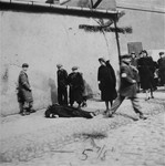 Warsaw ghetto residents stare at a man who has collapsed in the street.