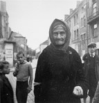 An elderly woman begs on the street in the Warsaw ghetto.