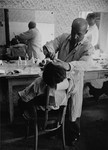 A barber gives a man a shave in the Bindermichl DP camp.