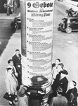 German pedestrians read a giant poster of Goering's "Nine Commandments for the Workers' Struggle," that has been affixed to a pillar in central Berlin.