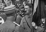 Grasping the "Blood Flag" in his hand, Adolf Hitler moves through the ranks of SA standard bearers at a 1934 Reichsparteitag (Reich Party Day) ceremony.