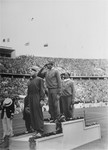 The winners of the 100m dash on the medal stand at the 11th Summer Olympic Games.