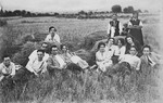 A group of young Bulgarian Jews rests by bundles of hay in the countryside where they have gone to help with the harvest.