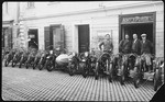 An Austrian-Jewish family stands before a row of motorcycles parked in front of their department store.