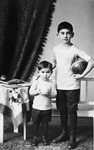 Studio portrait of two Austrian-Jewish brothers, Kurt and Paul Peter Porges, holding balls.
