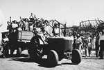 Teenage girls wave from a wagon pulled by a tractor in Tel Shachar.