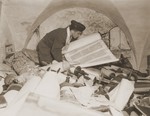 Chaplain Samuel Blinder examines one of the Torah scrolls stolen by the Einsatzstab Rosenberg and stored in the basement of the Institut fuer Juedische Erforschung [Institute for Research into the Jewish Question] in Frankfurt am Main.