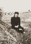 A young woman sits next to a haystack in the Zelow ghetto.