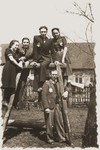 Group portrait of young Jewish men and women posing on a wooden structure in the Zelow ghetto.