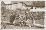Group portrait of young Jewish men and women seated on a log in the Zelow ghetto.