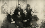 A group of six people poses in a living-room in prewar Krakow.