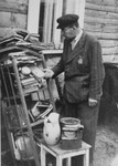 A Jew looks through discarded books piled outside a house in the Kovno ghetto.