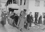 A Jewish policeman helps a family carry their luggage from the Abba Haskel synagogue to the assembly point for deportation in the Kovno ghetto.