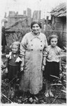 Sara Tyk (the mother of Shmuel) stands with two young girls in her yard.