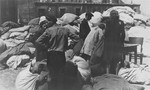 Jewish men and women prepare to sort  clothing that was confiscated from the deportees to the Chelmno death camp.