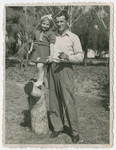 Yehuda Bielski poses with his daughter Nili who is standing on a tree stump.