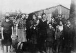 Group portrait of survivors of the Klooga concentration camp in front of a barracks.