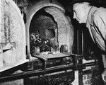 Congressman Ed V. Izak of California, a member of a Congressional delegation that traveled to Germany to view evidence of Nazi atrocities, looking at human remains in a crematorium oven.