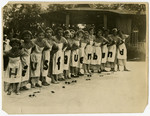 German school girls and members of the Hausfrauenbund (Housewife's club) pose wearing alphabet aprons.
