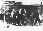 Jews are marched through town carrying bundles during a deportation action from Plonsk.