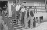 A group of Jewish youth pose on the stairs of a boathouse.