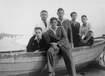 Five Jewish youth pose in a row boat at a vacation spot in Lithuania.