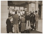 Austrian civilians view a display of photographs mounted in the window of a building in Linz showing Nazi atrocities in various concentration camps.