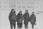 Four school boys carrying their school bags pose on a snowy street in the Kovno ghetto.