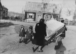 A woman pushes a cart piled with household belongings through the streets of the Kovno ghetto.