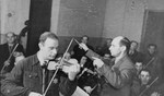 Performance of the Kovno ghetto orchestra. 

Pictured are Boris (Abraham, or Abrasha for short), Stupel, playing the violin and Michael Leo Hofmekler, conducting.