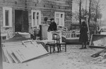 A Jew stands among disassembled furniture outside a house in the Kovno ghetto.