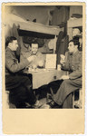 Jewish POWs play cards inside their barracks.

Max Beker is pictured on the right.