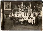 Members of the Lifschitz family pose with a group of Romanian peasants wearing embroidered vests that Avraham David Litschitz wove in his textile shop.