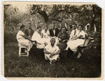 Prewar portrait of a group of family and friends sitting by a table outside.